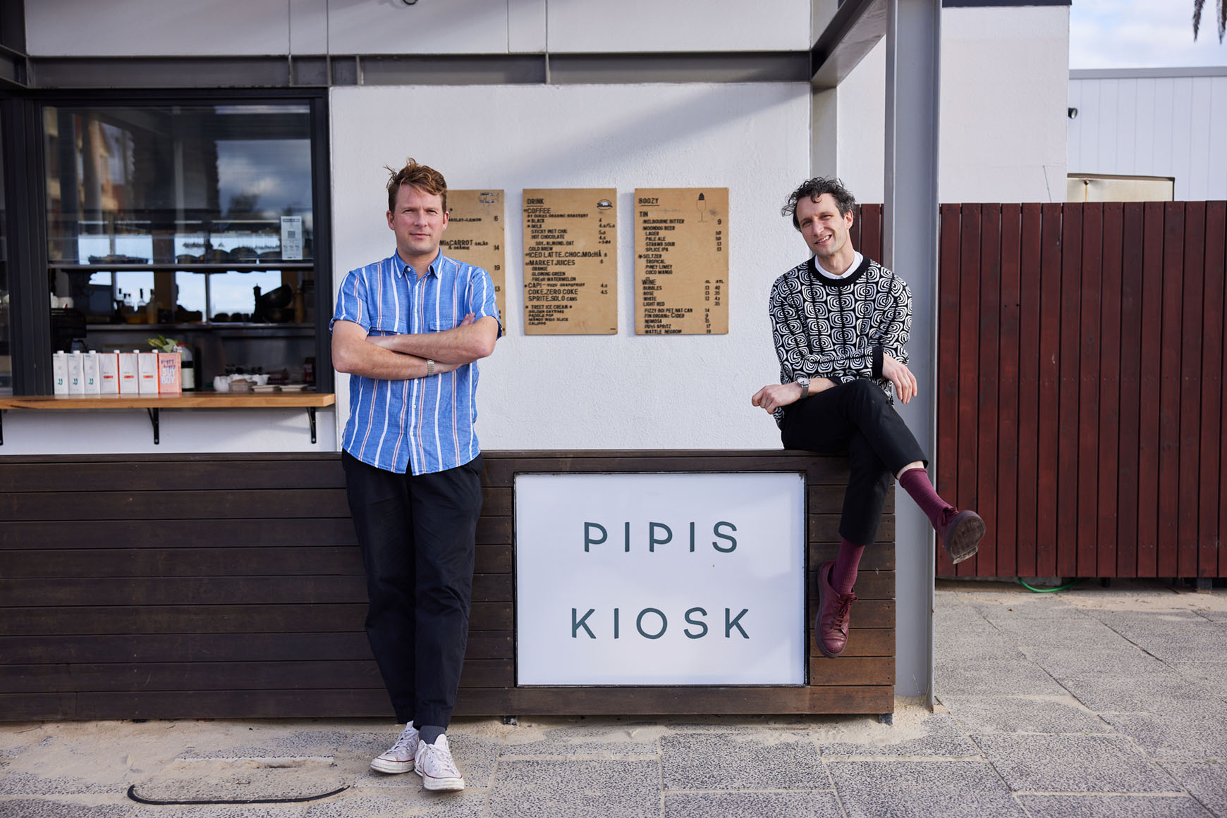Owners Jordan and Tom of Pipis Kiosk stand next to signage designed by Small and Co